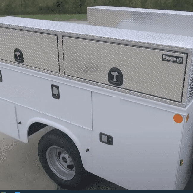 Diamond tread aluminum flop up tool box mounted on the side of a service body truck.