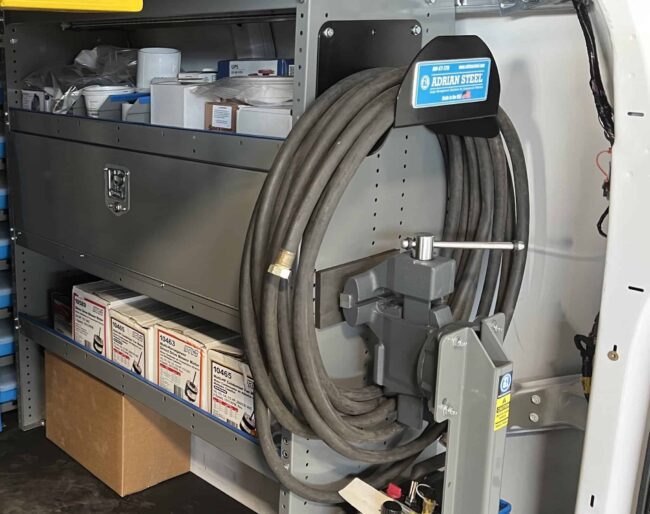 Front view of gray Adrian Steel hose holder shown with hose installed in end panel of van.