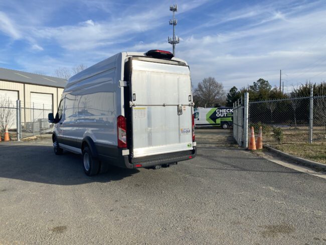 The back of a Ford Transit with the ramp liftgate and backdoors closed.